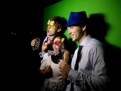 Τρεις καλεσμένοι ποζάρουν στο Smileme Photobooth κρατώντας παιχνίδια - props και φορώντας καπέλα σε γάμο στην Κασσιόπη Κέρκυρας