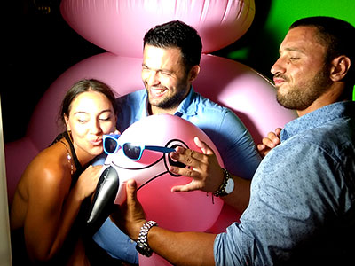 Καλεσμένοι φωτογραφίζονται στο Smileme Photobooth με φουσκωτό παιχνίδι φλαμίνγκο σε γάμο στο νησί των Παξών